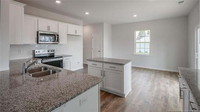 kitchen featuring sink, stone countertops, a center island, white cabinetry, and stainless steel appliances