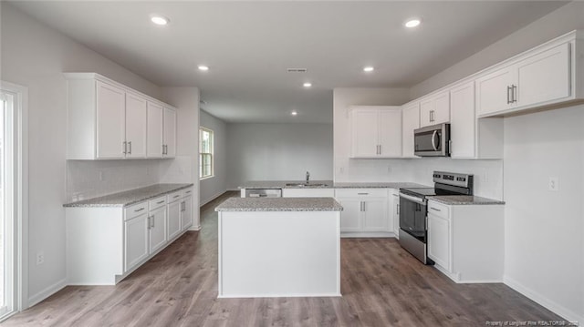 kitchen featuring white cabinetry, appliances with stainless steel finishes, a kitchen island, and light hardwood / wood-style floors