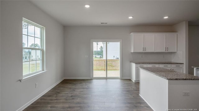 kitchen featuring light stone countertops, decorative backsplash, a center island, dark hardwood / wood-style flooring, and white cabinetry