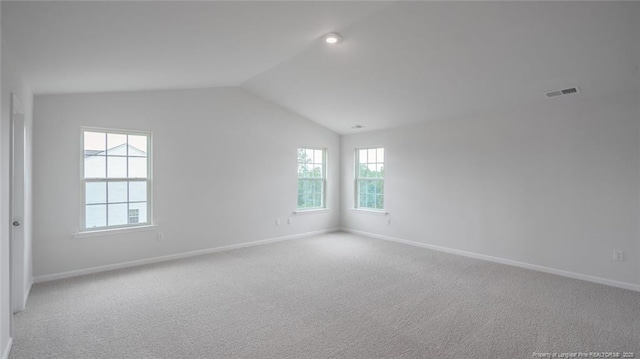 spare room featuring light carpet and lofted ceiling