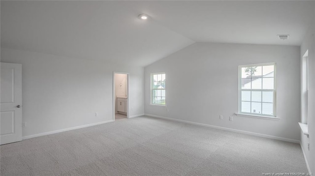 unfurnished bedroom with vaulted ceiling, light colored carpet, and ensuite bath