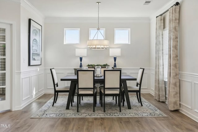 dining area with ornamental molding, a healthy amount of sunlight, visible vents, and wood finished floors