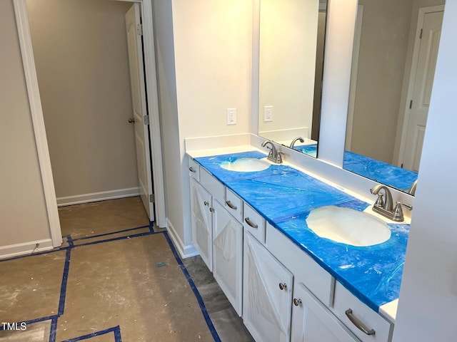 bathroom with concrete flooring, double vanity, and baseboards