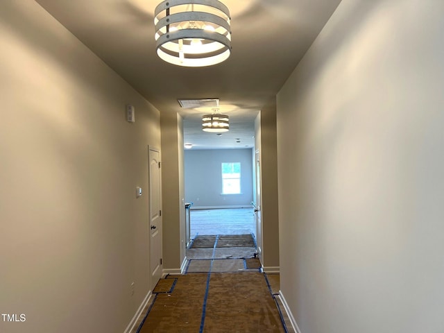 hall with baseboards and a chandelier