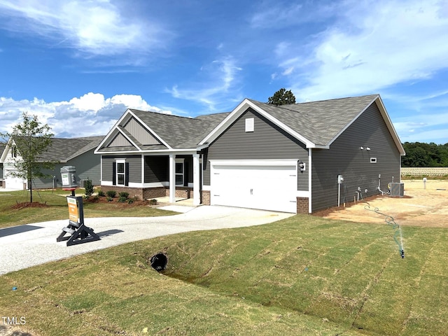 ranch-style home with roof with shingles, cooling unit, a garage, and a front lawn