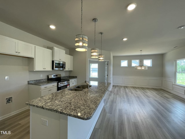 316 Olivia Crossing Ct Unit 11, Four Oaks, NC 27524 - kitchen featuring appliances with stainless steel finishes, a sink, white cabinets, wood finished floors, and wainscoting