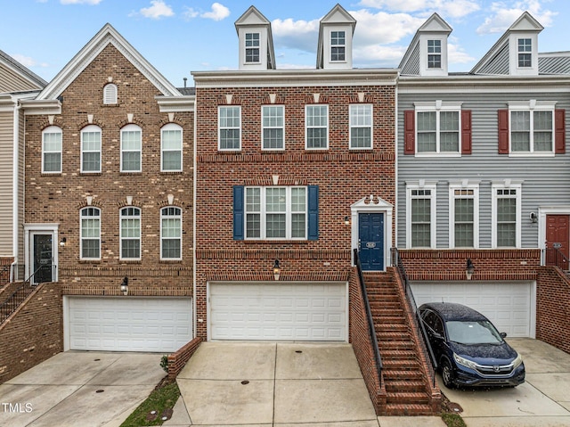 multi unit property with driveway, an attached garage, and brick siding