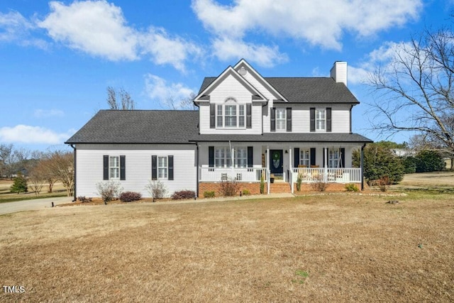 view of front facade with a shingled roof, a chimney, a front lawn, and a porch