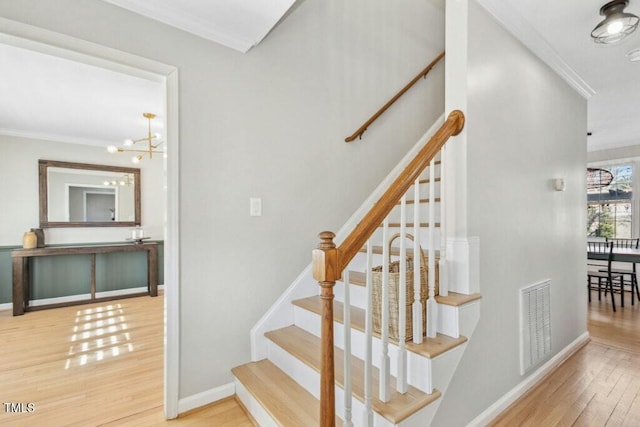 stairs with visible vents, crown molding, and wood finished floors