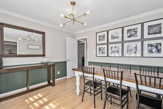 dining space with a chandelier, ornamental molding, and light wood-type flooring