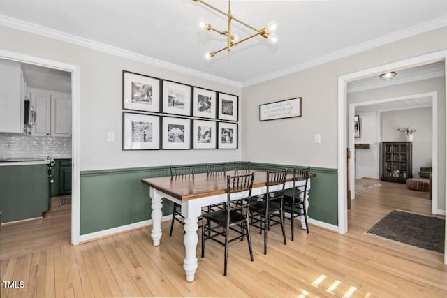 dining area featuring baseboards, crown molding, light wood finished floors, and an inviting chandelier