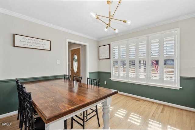 dining area with a chandelier, crown molding, baseboards, and wood finished floors