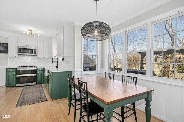 dining space with a healthy amount of sunlight, light wood-type flooring, and crown molding