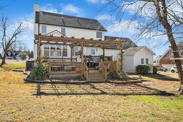 rear view of house with a chimney, a wooden deck, a lawn, and a pergola