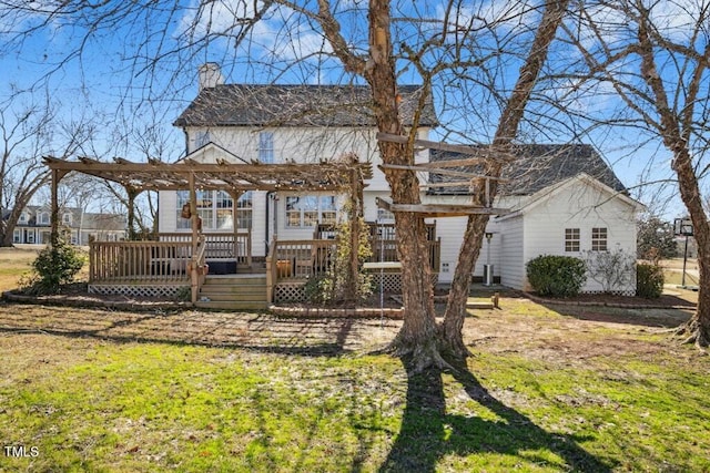 back of house with a chimney, a wooden deck, a lawn, and a pergola