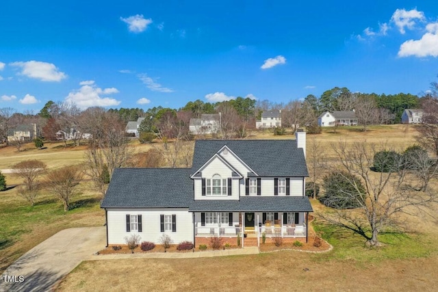 view of front of home with a chimney, a shingled roof, covered porch, a front yard, and driveway