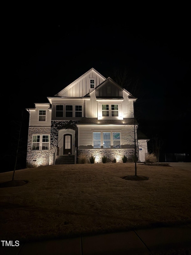 view of front of property featuring a yard, board and batten siding, and stone siding