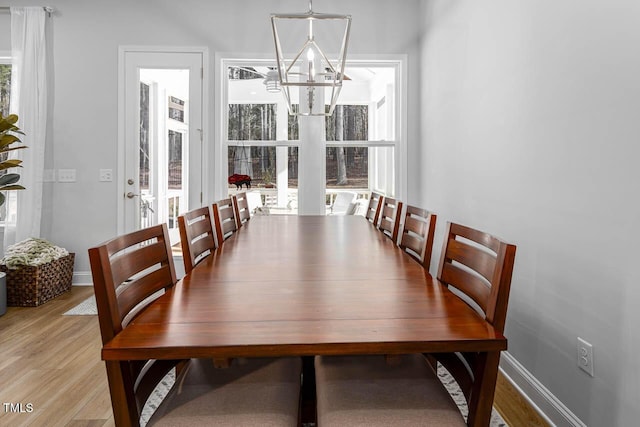 dining area featuring an inviting chandelier, light wood-style flooring, and baseboards