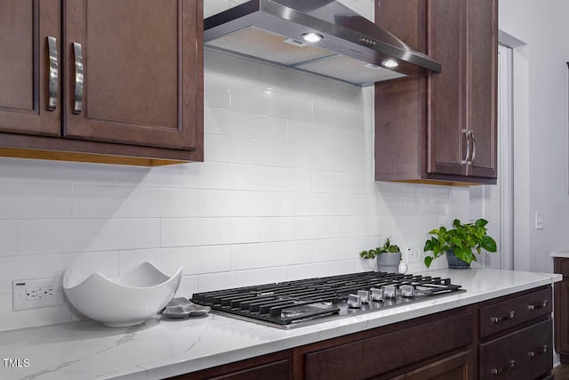 kitchen with stainless steel gas cooktop, dark brown cabinetry, and wall chimney range hood