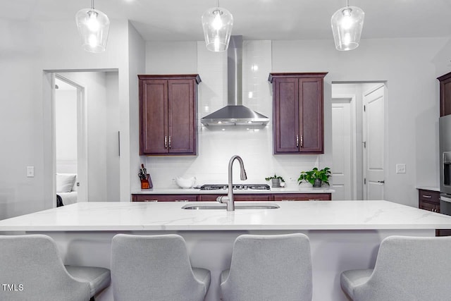 kitchen with decorative light fixtures, decorative backsplash, a breakfast bar area, and wall chimney range hood