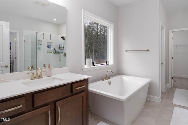 full bathroom with tile patterned floors, a freestanding tub, a shower stall, a spacious closet, and vanity