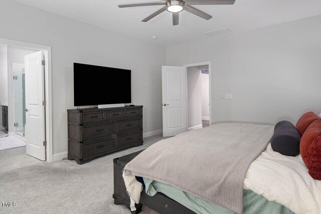 bedroom featuring visible vents, baseboards, ceiling fan, light colored carpet, and ensuite bathroom