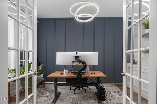 office space with french doors, wood finished floors, and a decorative wall