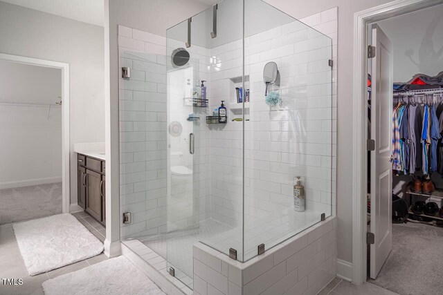 full bath featuring tile patterned flooring, a shower stall, vanity, and baseboards