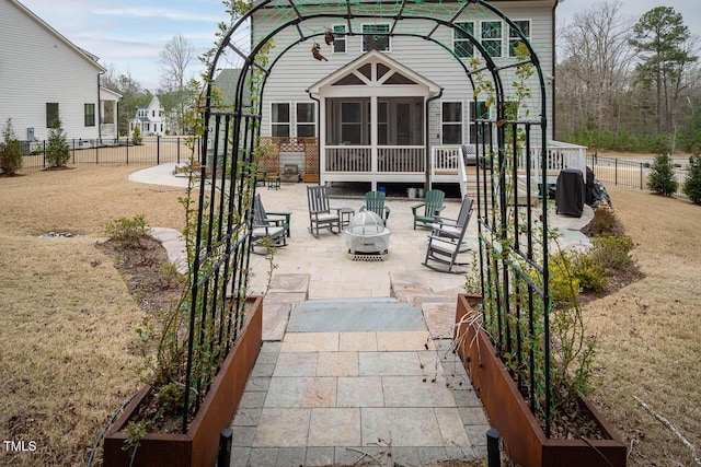 view of patio featuring fence, a fire pit, and a sunroom