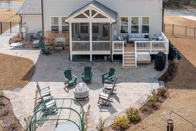 back of house with a shingled roof, an outdoor living space with a fire pit, fence private yard, a sunroom, and a patio area