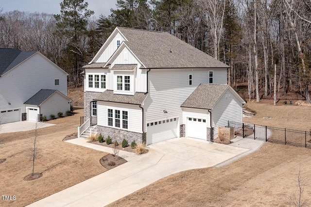 view of front of property featuring board and batten siding, fence, roof with shingles, a garage, and stone siding