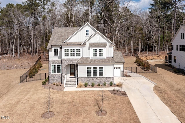 view of front facade featuring board and batten siding, a front lawn, fence, stone siding, and driveway