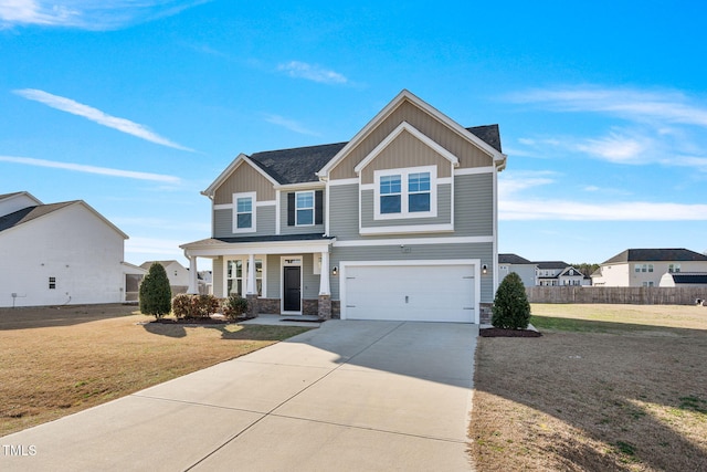 craftsman-style house featuring an attached garage, concrete driveway, stone siding, board and batten siding, and a front yard