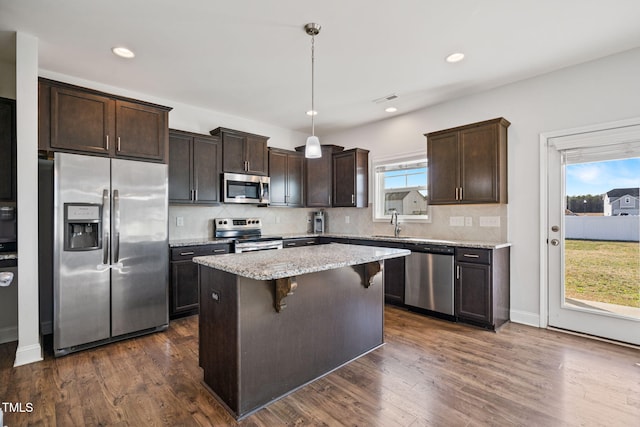 kitchen with a center island, a sink, dark brown cabinetry, backsplash, and appliances with stainless steel finishes