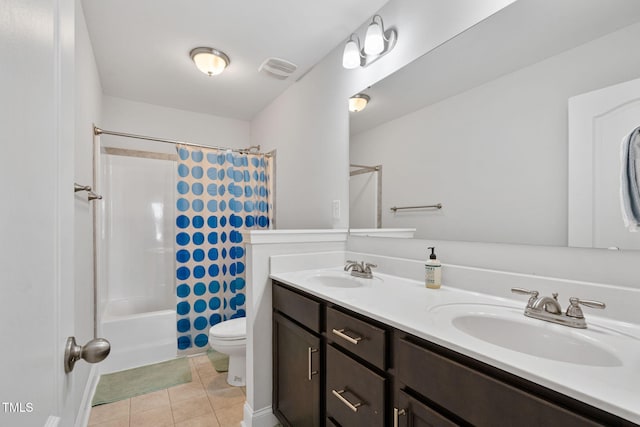 bathroom with toilet, tile patterned floors, a sink, and double vanity