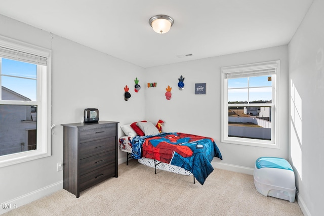 carpeted bedroom featuring visible vents, baseboards, and multiple windows