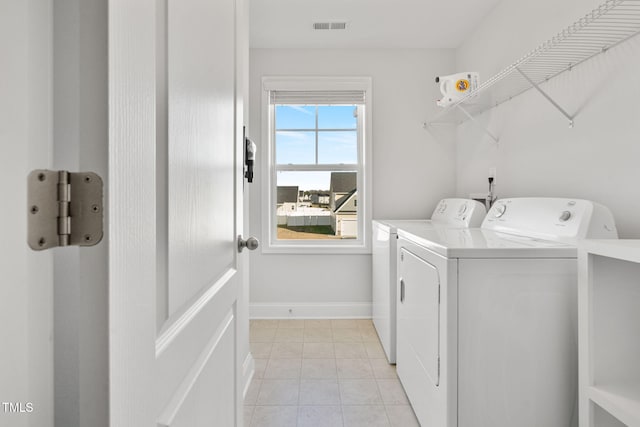 clothes washing area featuring separate washer and dryer, light tile patterned floors, visible vents, baseboards, and laundry area