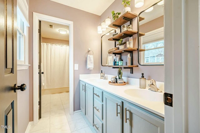 bathroom featuring double vanity, baseboards, visible vents, and a sink