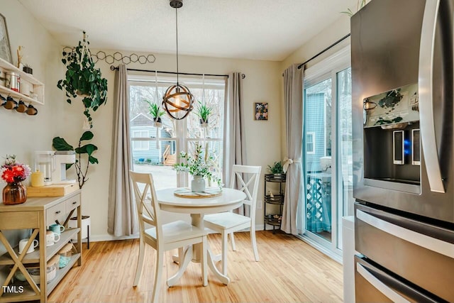 dining room with light wood-style flooring, baseboards, and a textured ceiling