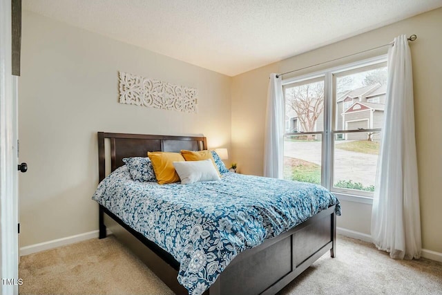 bedroom with light carpet, a textured ceiling, and baseboards