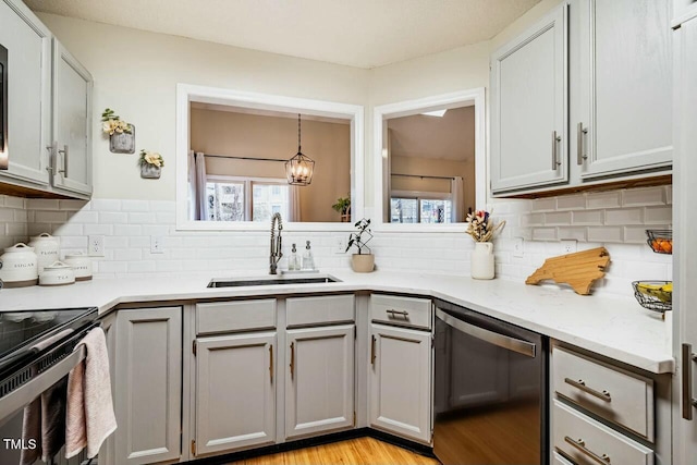 kitchen with stainless steel dishwasher, a sink, a wealth of natural light, and pendant lighting