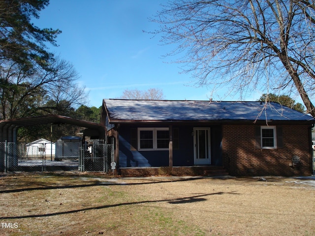 view of front facade with brick siding, a detached carport, entry steps, a front yard, and fence