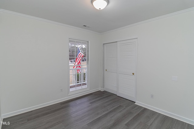 unfurnished bedroom with baseboards, a closet, ornamental molding, and dark wood-style flooring