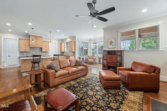 living area with recessed lighting, crown molding, baseboards, and wood finished floors