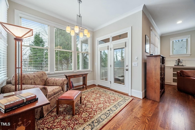 interior space featuring baseboards, ornamental molding, a chandelier, and wood finished floors