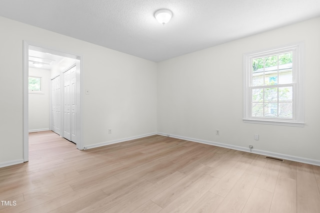 unfurnished room with light wood-style flooring, healthy amount of natural light, and baseboards