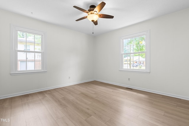 empty room with healthy amount of natural light, light wood-style floors, a ceiling fan, and baseboards