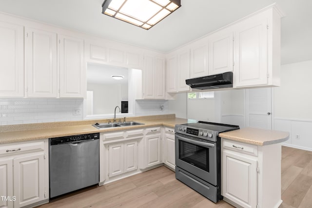 kitchen featuring stainless steel appliances, under cabinet range hood, a sink, light countertops, and light wood-style flooring