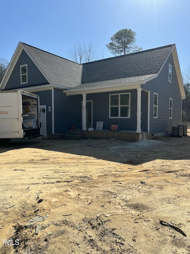 view of front of property with covered porch, central AC unit, and roof with shingles