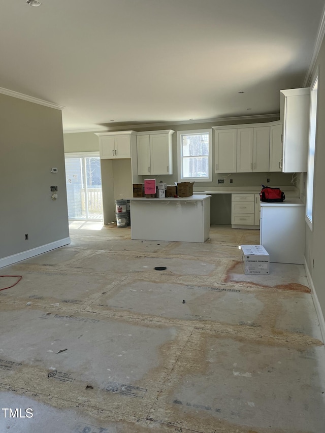 kitchen featuring baseboards, a kitchen island, white cabinets, and ornamental molding